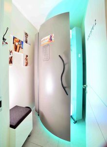 חדר שיזוף עם דלת מעוגלת בצבע אפור, מואר באור ירוק, עם פוסטרים על הקירות. חדר שיזוף עם דלת מעוגלת בצבע אפור, מואר באור ירוק, עם פוסטרים על הקירות.